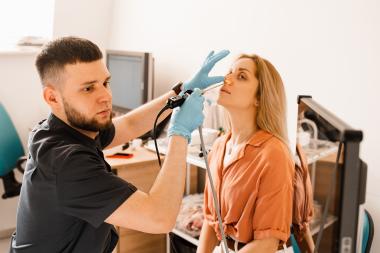 Nurse using fiberoptic endoscopy equipment on patient